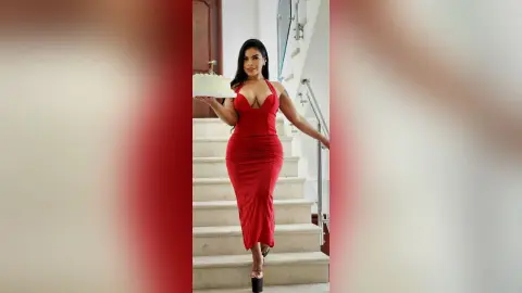 Elegant woman in a red halter maxi dress posing on white stairs for a glamorous evening look.