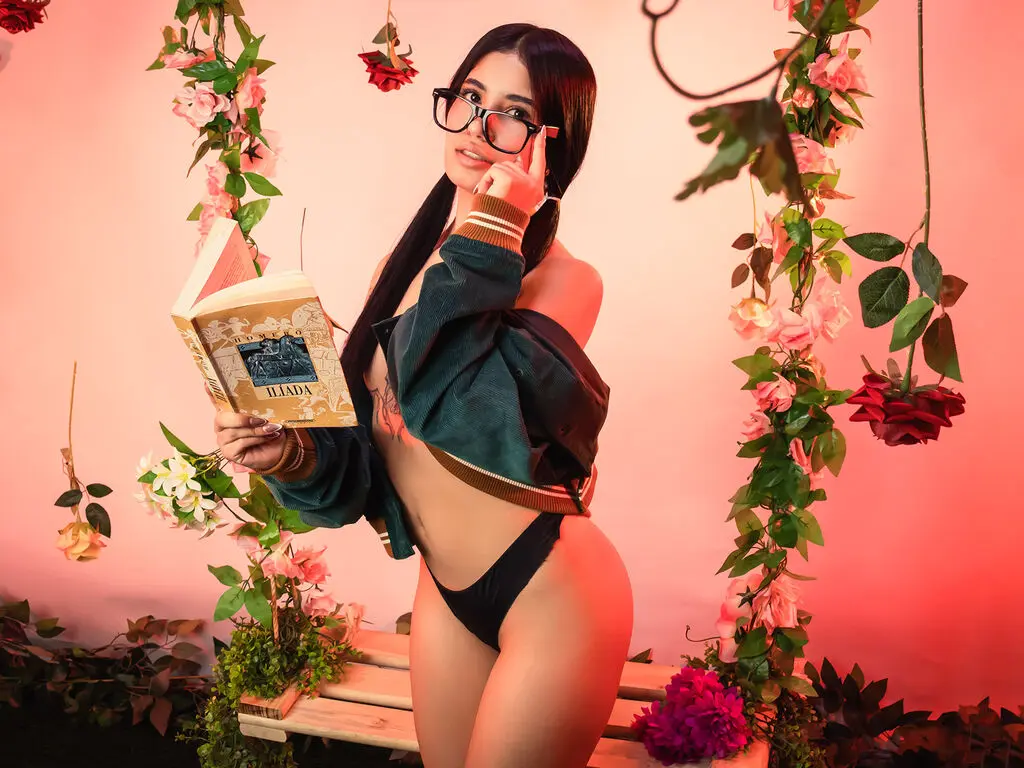 Young woman in a green cardigan reading a book amidst hanging roses in a romantic, warm-lit setting.