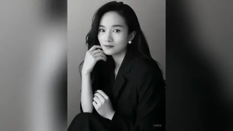Elegant woman in a black blazer posing with a thoughtful expression in a minimalist black and white portrait.