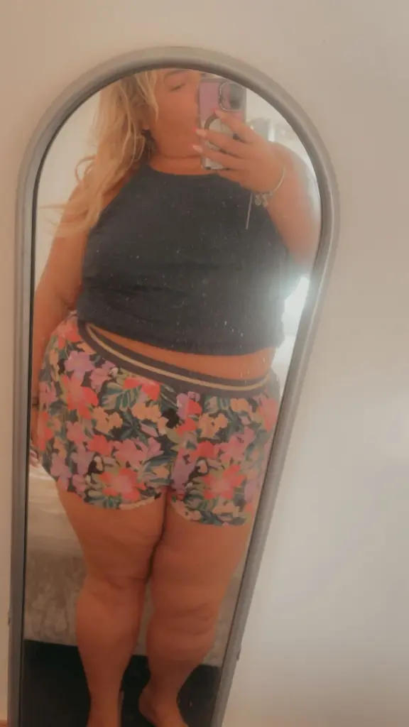 Naughty_Laurenx poses close up, showing her face and pink braided hair while wearing a light green sleeveless top.
