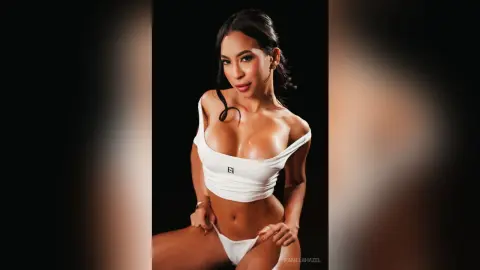 Beautiful woman in white bikini top and briefs posing against a black background with a confident mood.