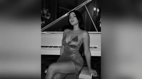 Elegant woman in a sleek satin slip dress sitting by a grand piano in a moody, sophisticated setting.