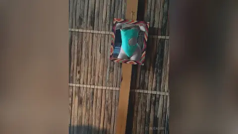 Woman in a turquoise swimsuit reflected in a mirror against a rustic bamboo wall in a tropical setting.