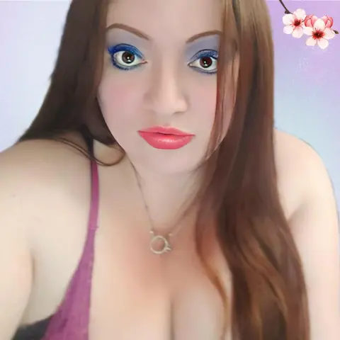 Young woman with long brown hair and blue eyeshadow wearing a purple tank top in a soft, bright setting.
