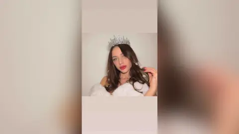 Elegant woman in a white fuzzy outfit and silver crown posing with a dreamy, regal mood.