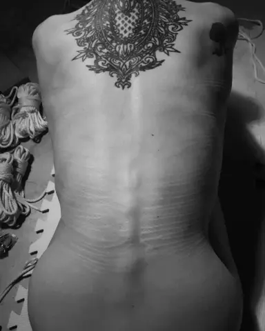 GoddessEvaEvangelista shows her bare back and large, detailed black ink tattoo, ornately patterned, against her skin.