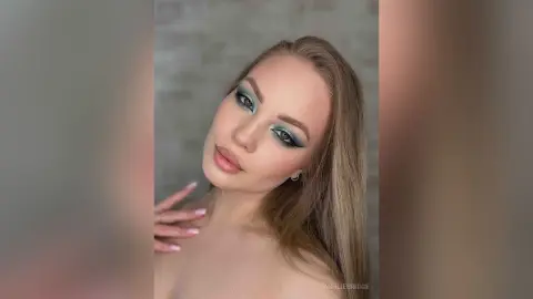 Young woman with teal eyeshadow and long blonde hair posing for a glamorous beauty portrait.
