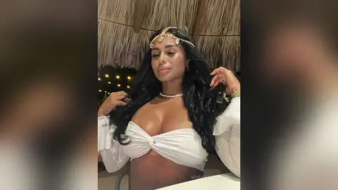Beautiful woman in white bohemian outfit and gold headpiece posing in a tropical outdoor setting.
