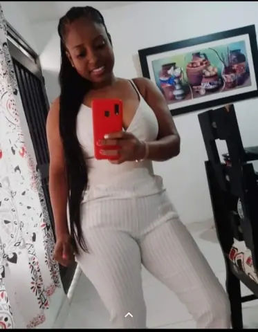 HellenJohansson — Smiling woman in a white ribbed two-piece outfit taking a mirror selfie in a bright modern room.