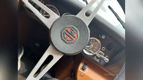 Close-up of a vintage MG steering wheel and classic car dashboard interior with retro gauges.