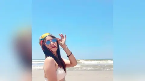 Young woman in white bikini and sunglasses enjoying a sunny summer day at the beach.