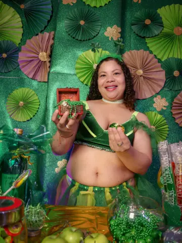 Smiling woman in green St. Patrick's Day outfit holding a small treasure box in a festive green setting.