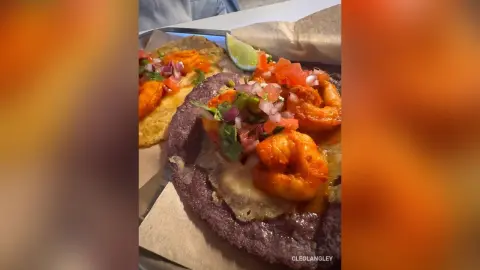 Delicious shrimp tostada with fresh salsa and lime on a rustic paper plate in a warm restaurant setting.