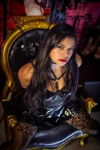 Moody portrait of a woman in black lace lingerie sitting on a vintage gold and black armchair.