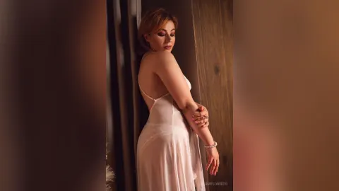 AmeliaReds — AmeliaReds poses in a sheer white nightgown while leaning against a wooden wall.