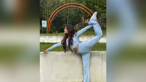 TefyRusso shows off her flexibility, posing in a light blue athletic set while doing a high leg stretch outdoors.