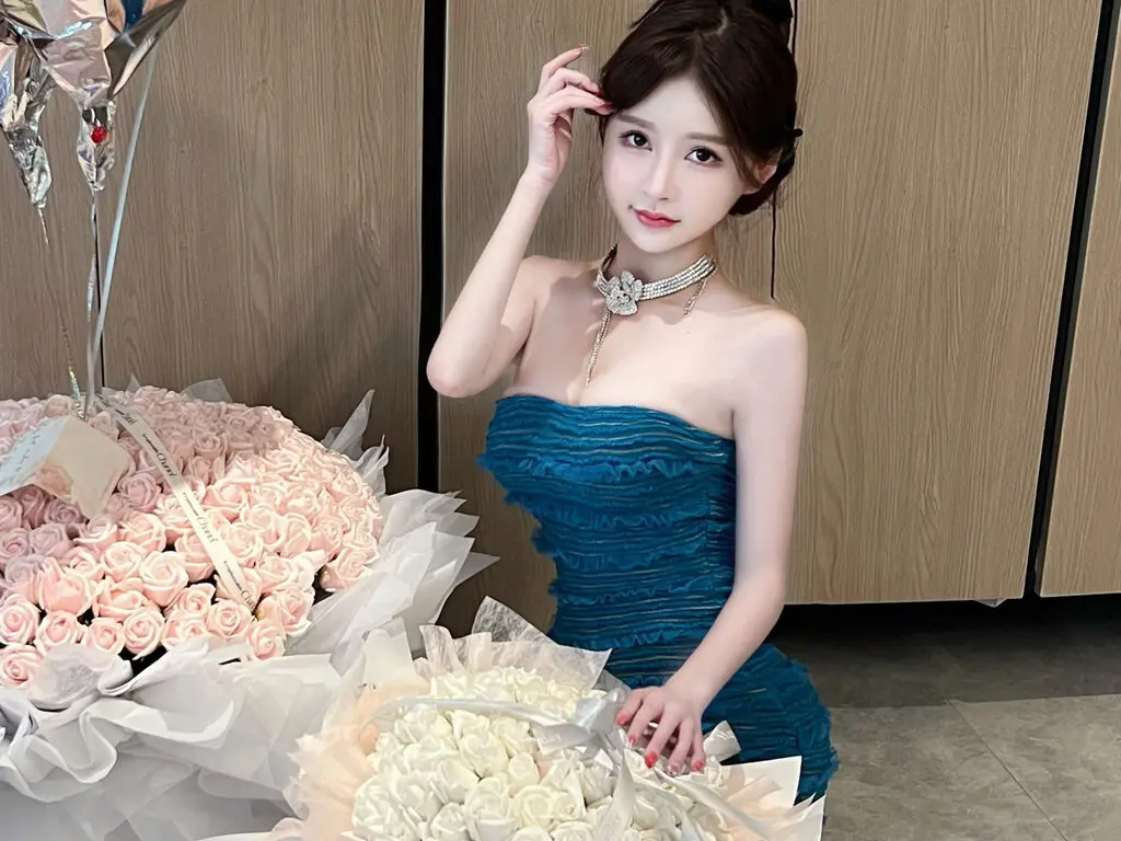 Elegant woman in a teal strapless ruffled dress posing with large bouquets of pink and white roses.