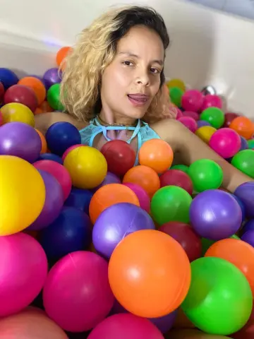 Blonde woman relaxing in a colorful ball pit for a playful and joyful summer mood.