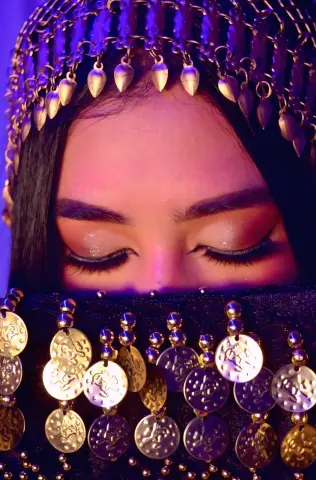Close-up of a woman in traditional gold coin jewelry and dark ethnic attire with a mystical mood.