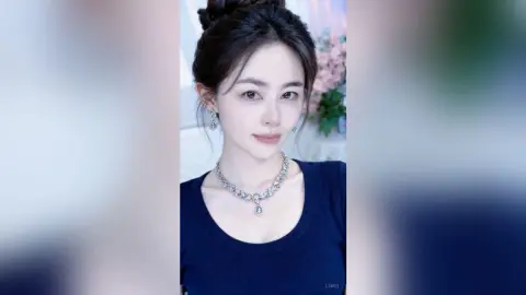 Elegant woman in a navy blue top wearing a sparkling silver diamond necklace and matching earrings.