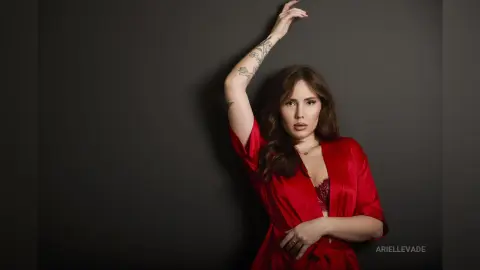 Elegant woman in a red silk robe posing against a dark background with a moody, sophisticated vibe.