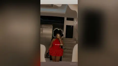 Stylish woman in a red ruffled mini dress standing in a modern luxury home interior.