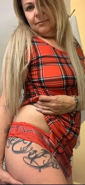 SavannahSlater poses in a red plaid shirt, pulling the fabric down to show her bare skin and stomach.