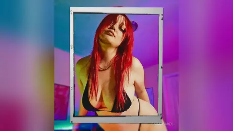 Red-haired woman in a black bikini posing confidently in a dreamy pink and blue neon lit room.