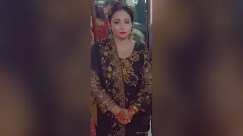 Elegant woman in a black and gold embroidered traditional Indian lehenga posing in a warm indoor setting.