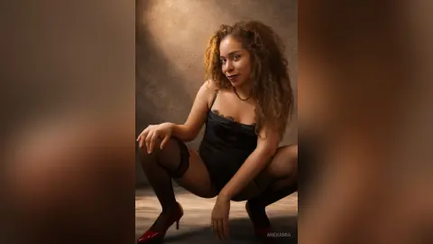 Smiling woman in a black bodysuit and stockings posing against a warm, moody studio background.