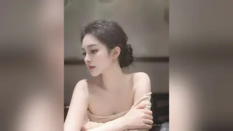 AgelaHui poses with her hair in a bun, wearing a white cloth wrapped around her chest and arms.