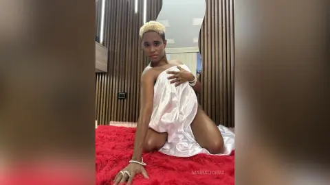 Elegant woman in a white satin wrap sitting on a red shaggy rug in a modern room.