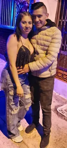 Happy young couple in casual evening outfits posing together outdoors at night.