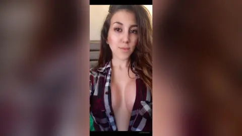 Young woman in a red plaid flannel shirt posing indoors with a relaxed, natural expression.