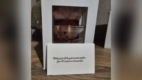 Elegant gift box containing a luxury scented candle with a heartfelt handwritten thank you note on a wooden table.