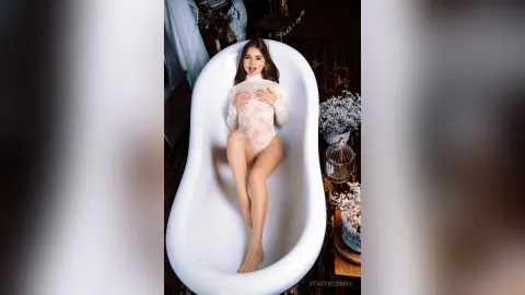 StasyScorpio — StasyScorpio poses in a white lace bodysuit while reclining inside a large white bathtub.