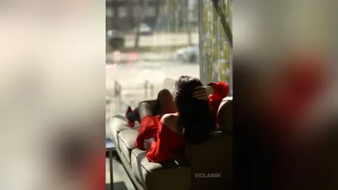 ViolaWin — ViolaWin relaxes on a tan sofa in a red dress with her dark hair flowing down her back.