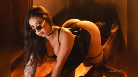 MilaWillow poses on all fours in a black dress and sunglasses, showing off her curves and large ass.