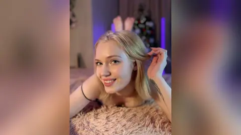 Smiling blonde woman in a black top relaxing on a cozy shag rug in a room with purple ambient lighting.