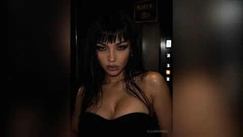 Moody portrait of a brunette woman in a black strapless top standing in a dark hotel hallway.