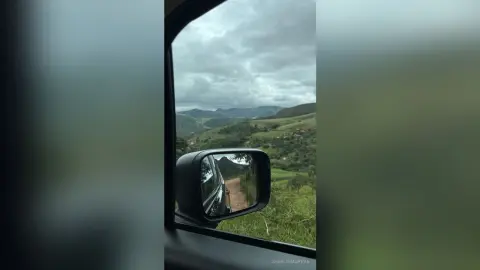 Scenic mountain landscape view through a car side mirror on a cloudy day during a road trip.