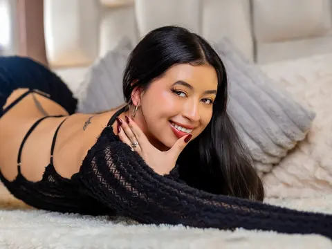 Smiling young woman in a black lace bodysuit relaxing on a cozy white faux fur bed.