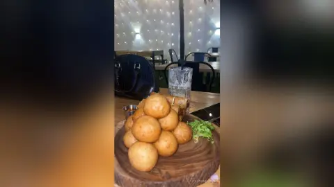 Golden fried potato croquettes served on a wooden platter in a dimly lit restaurant setting.