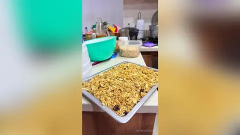 Homemade granola cereal in a large silver baking tray on a kitchen counter.