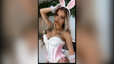 Glamorous woman in white bunny ears and lace corset outfit posing in a bright indoor setting.