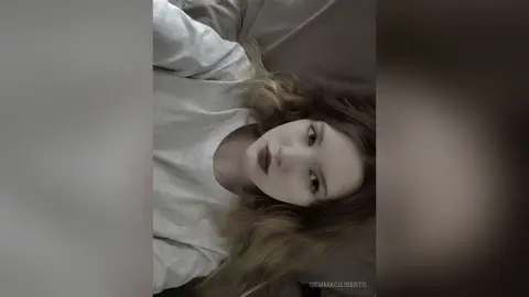 GemmaCiliberto lying down with her long blonde hair spread out, wearing a white long-sleeved shirt.