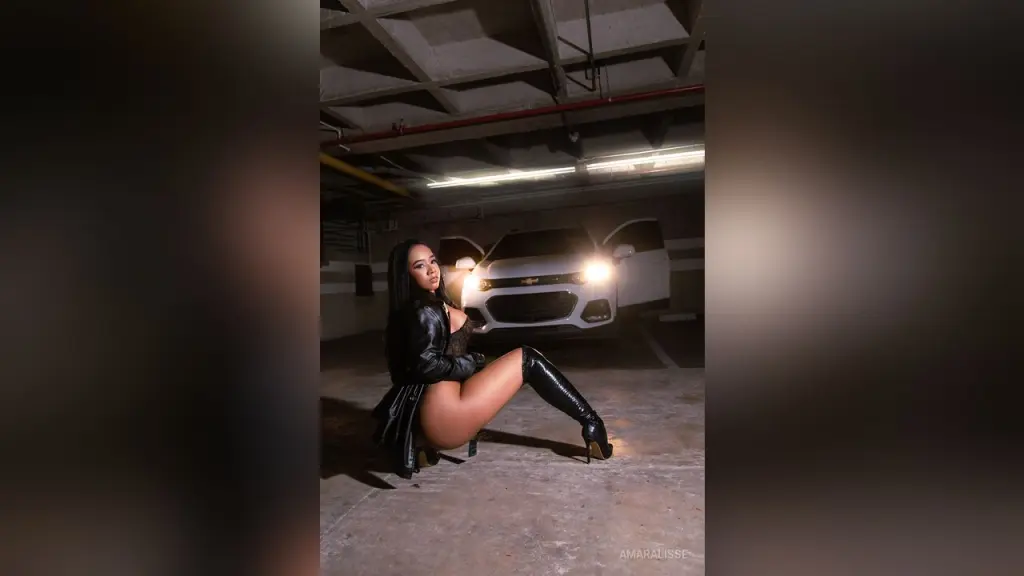 AmaraLisse — AmaraLisse poses in a garage wearing a black leather jacket and thigh-high black boots.