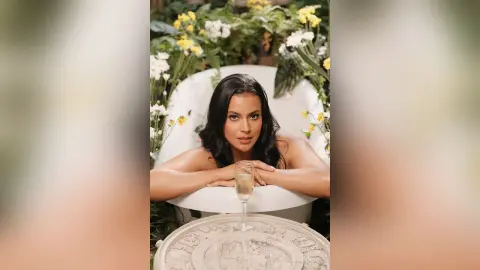 Beautiful woman relaxing in a white bathtub surrounded by yellow flowers for a dreamy, botanical aesthetic.