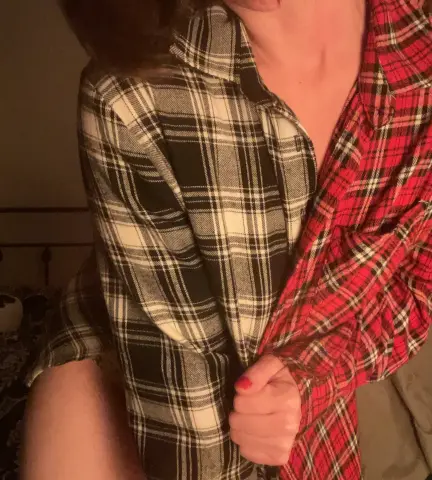 MartaShadow wears a black and white plaid flannel shirt, partially open to show her chest and neck.