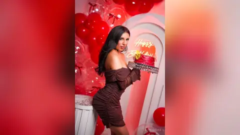 Woman in a brown off-the-shoulder dress celebrating a birthday with red balloons and a cake in a festive mood.